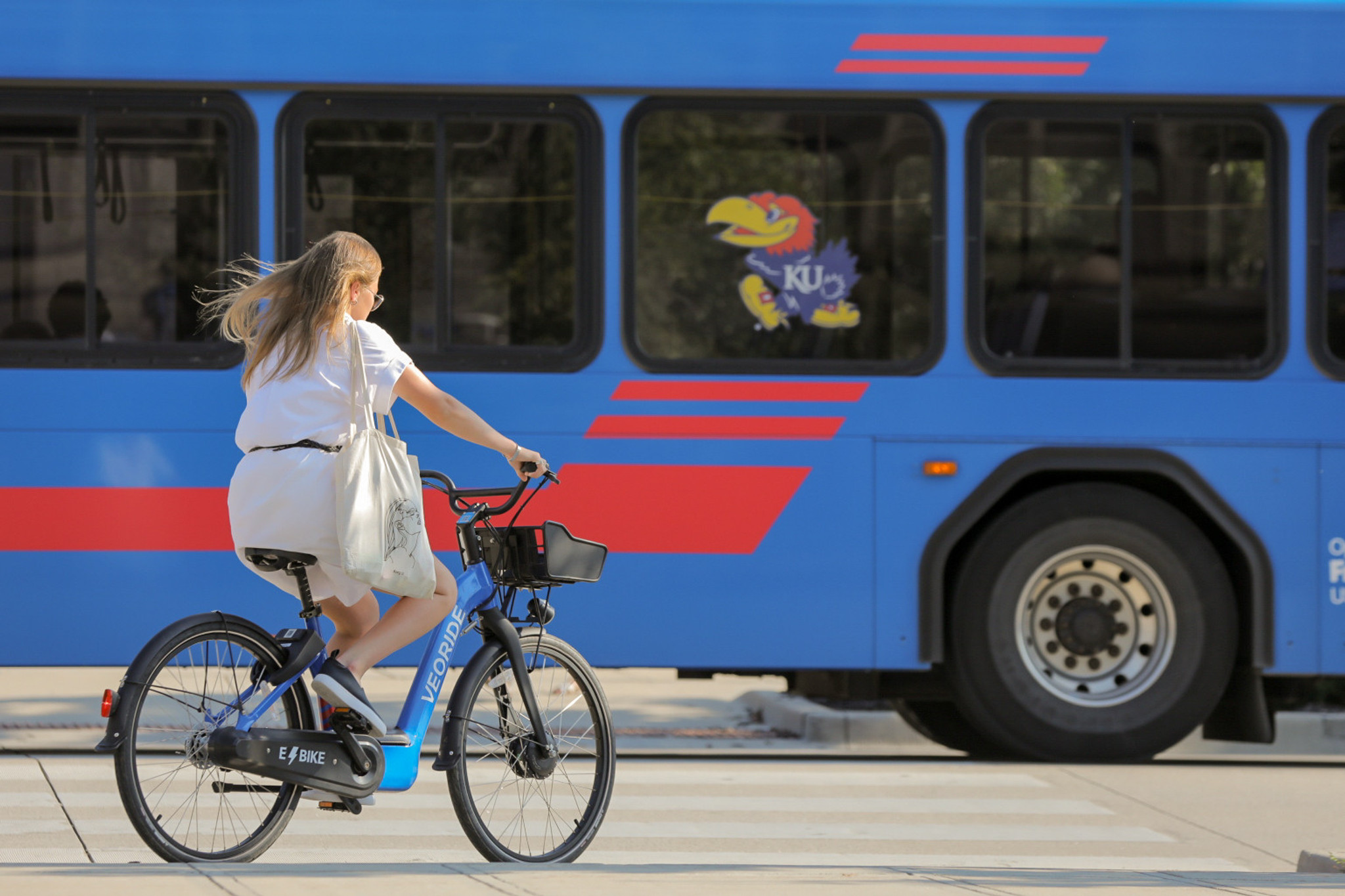 A woman rides her bike as a bus passes.